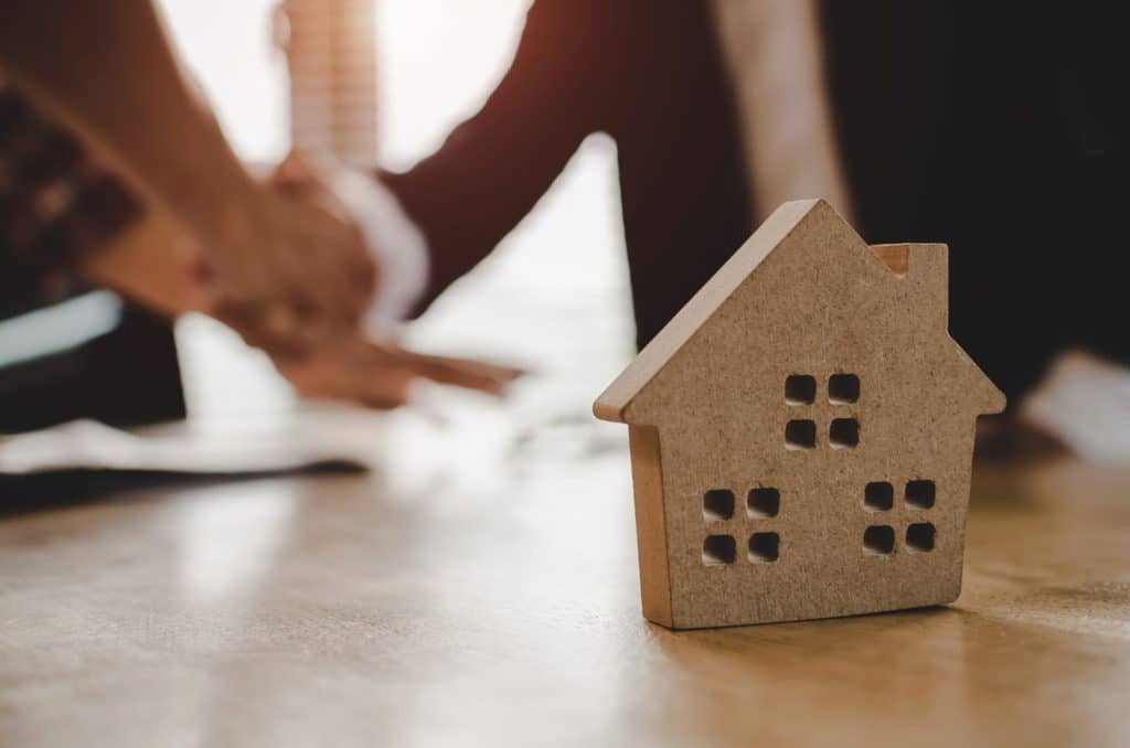 A real estate agent and a couple shake hands | Sewell Sewell Beard LLC