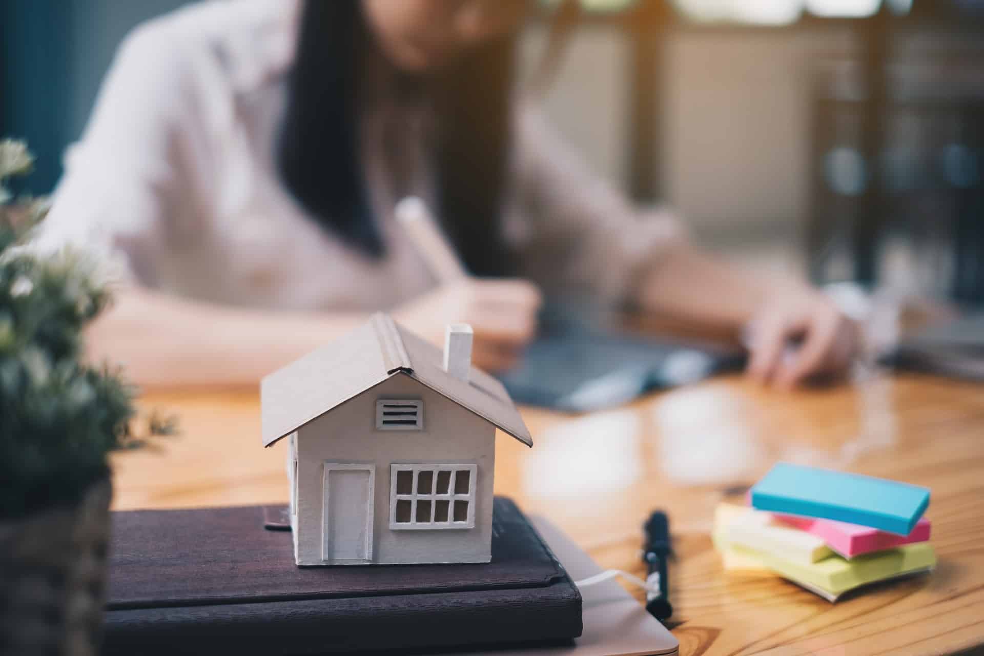 A working woman sitting behind a house model | Sewell Sewell Beard LLC