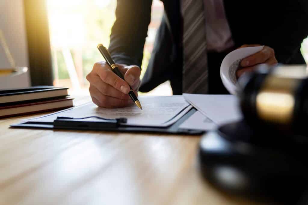 A man in a suit is signing a document on a desk | Sewell Sewell Beard LLC