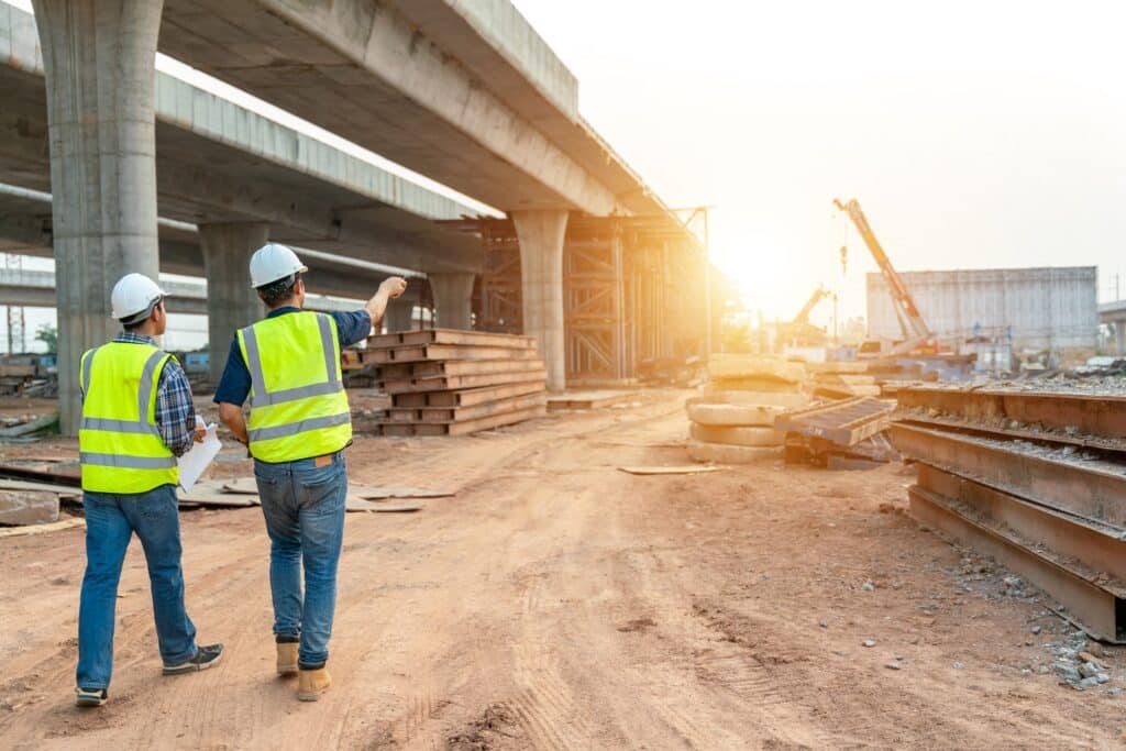 Two construction workers standing under an overpass | Sewell Sewell Beard LLC