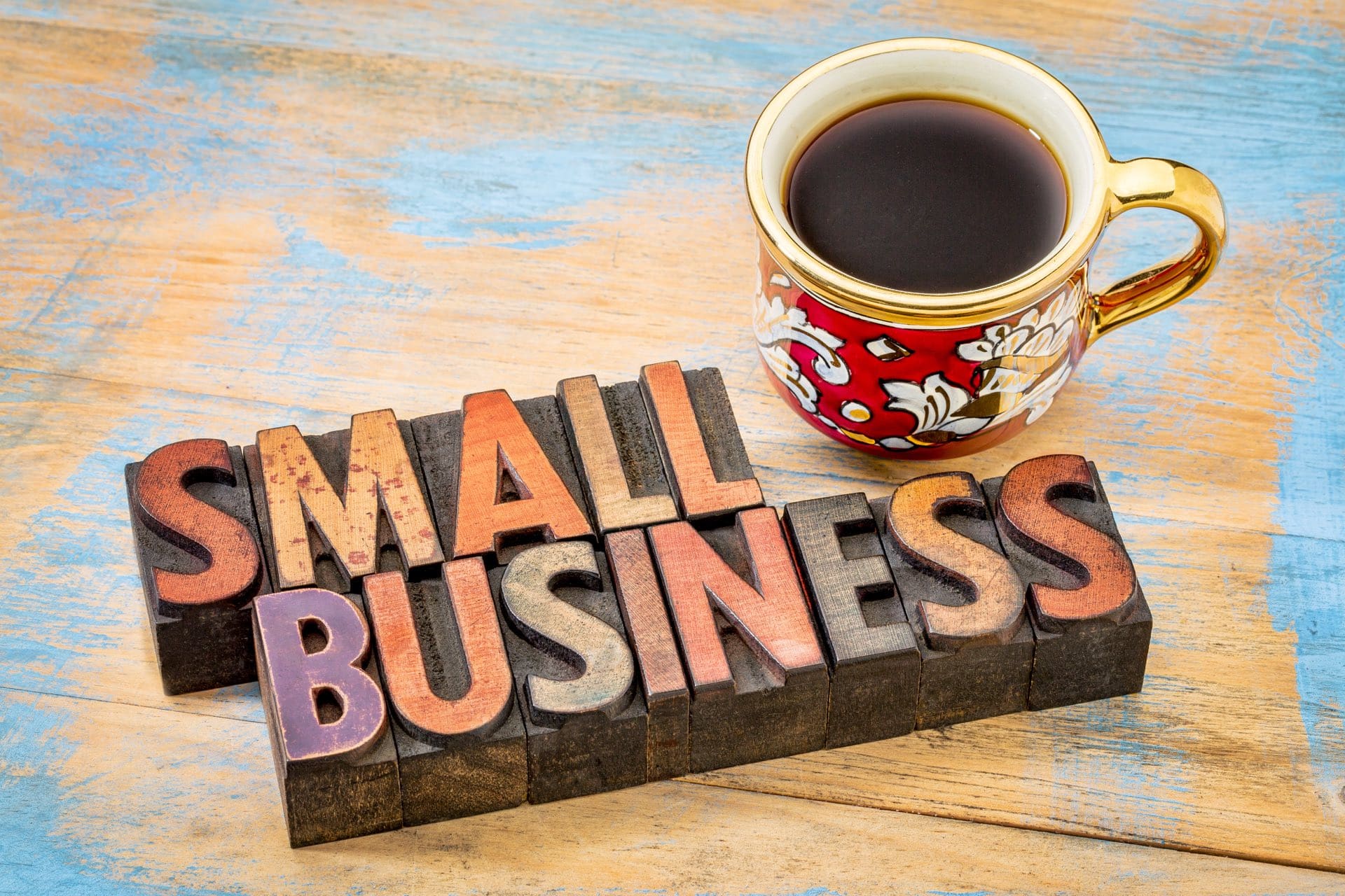 Wooden block that says small business next to a cup of coffee