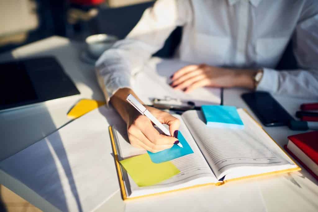 A woman writing in a notebook with a pen | Sewell Sewell Beard LLC