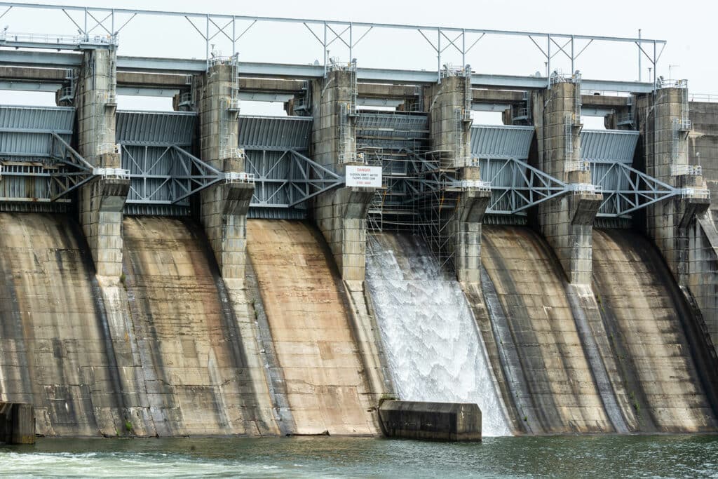 A massive dam with water spilling over its top | Sewell Sewell Beard LLC