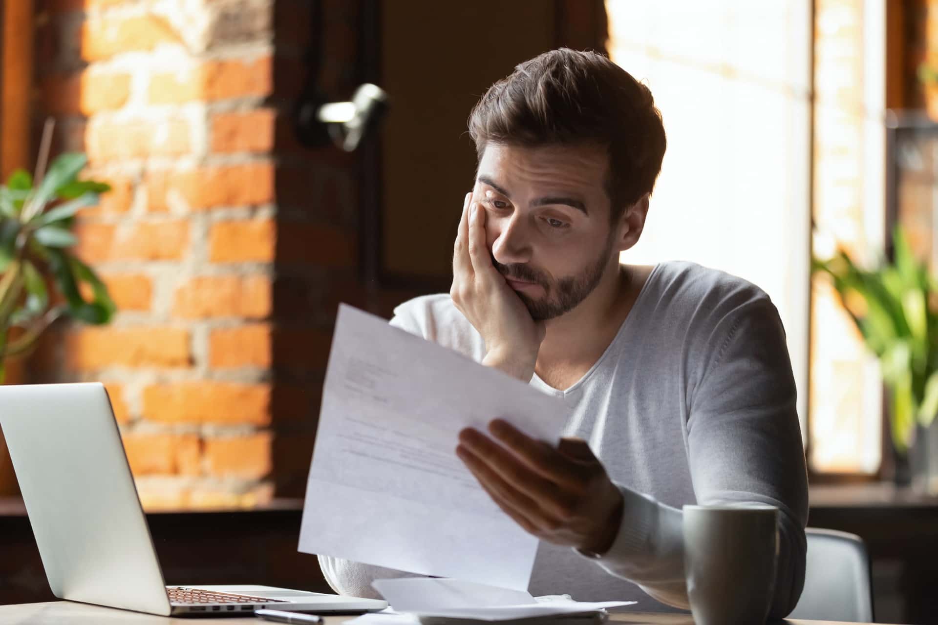 A man with hand on face staring at a legal document