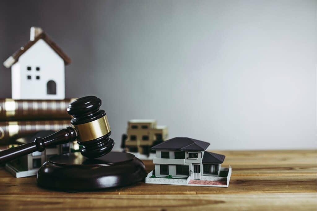 A judge's gavel on a wooden table with model houses | Sewell Sewell Beard LLC