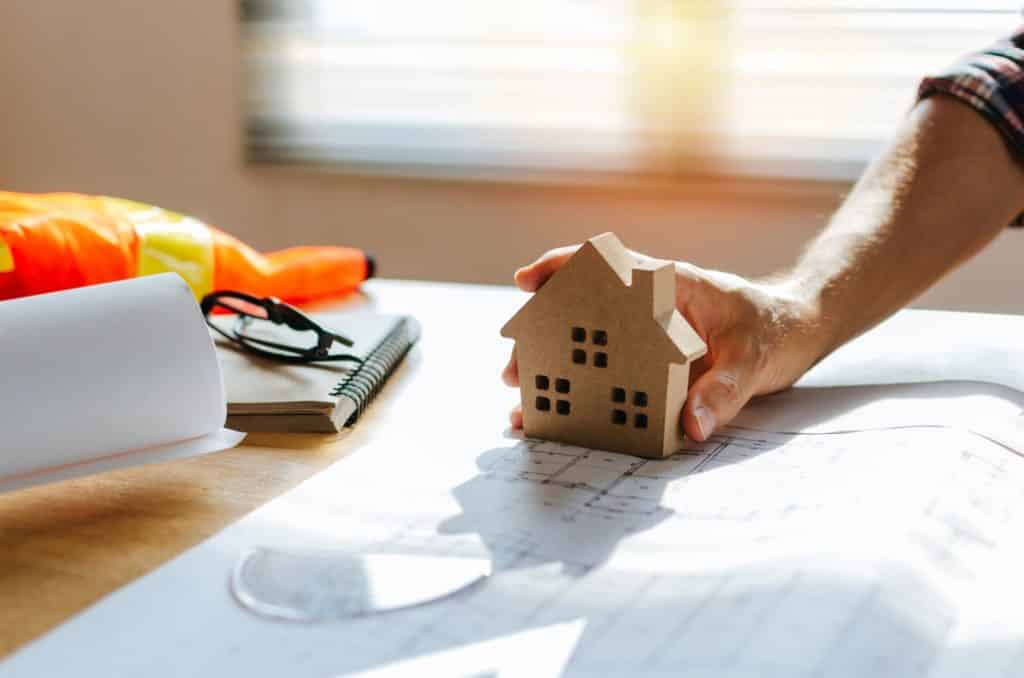 A man holds a small house model on a table | Sewell Sewell Beard LLC