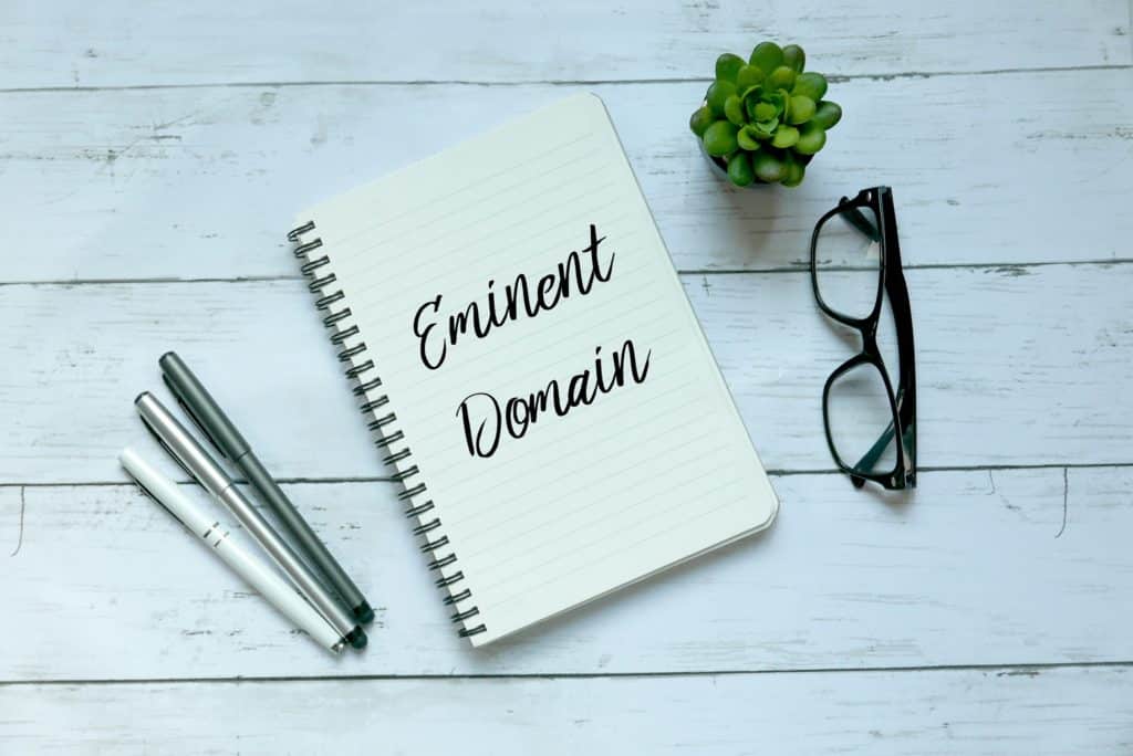 A notebook with 'eminent domain' next to pens & glasses | Sewell Sewell Beard LLC