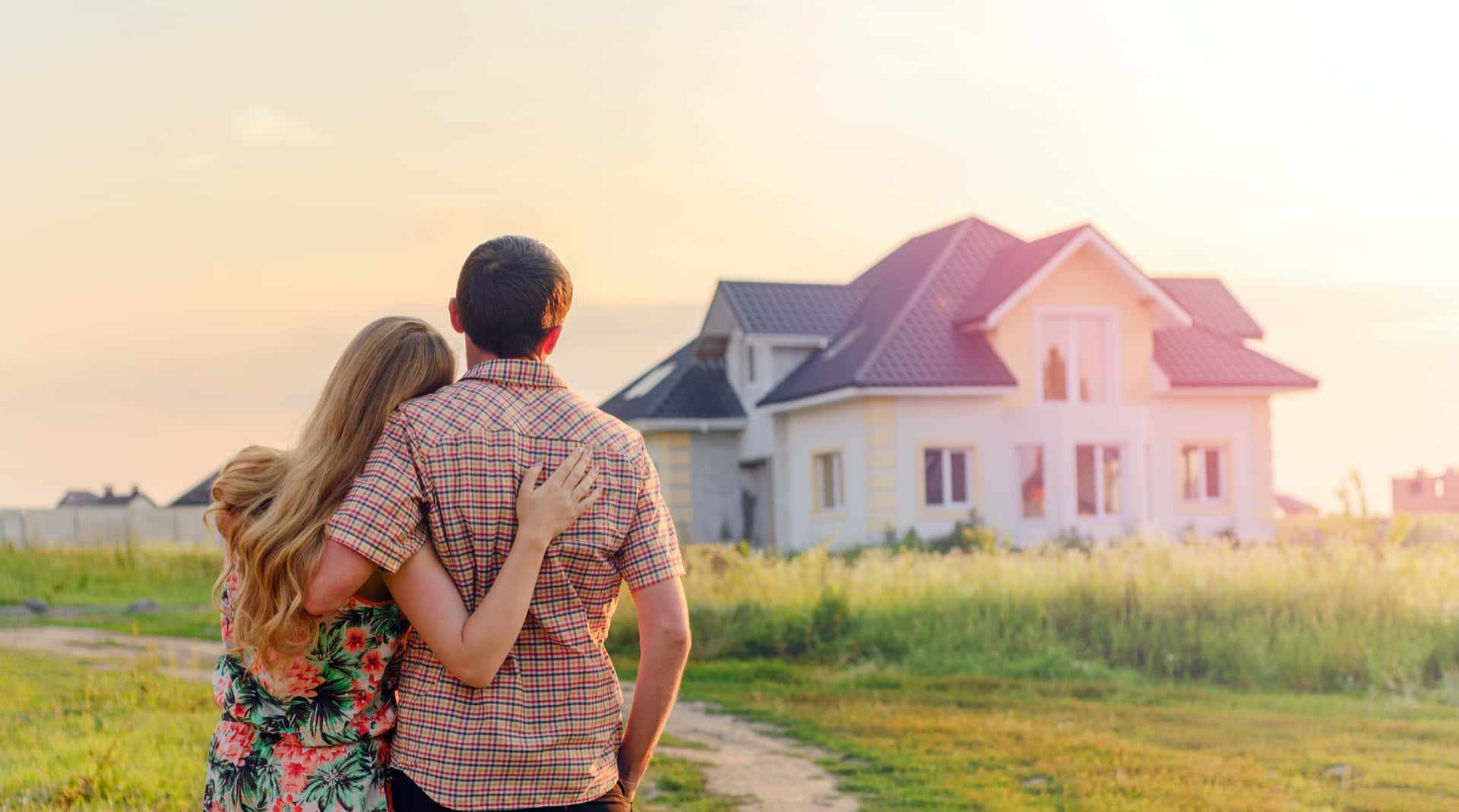 Man and woman hugging in front of new home construction